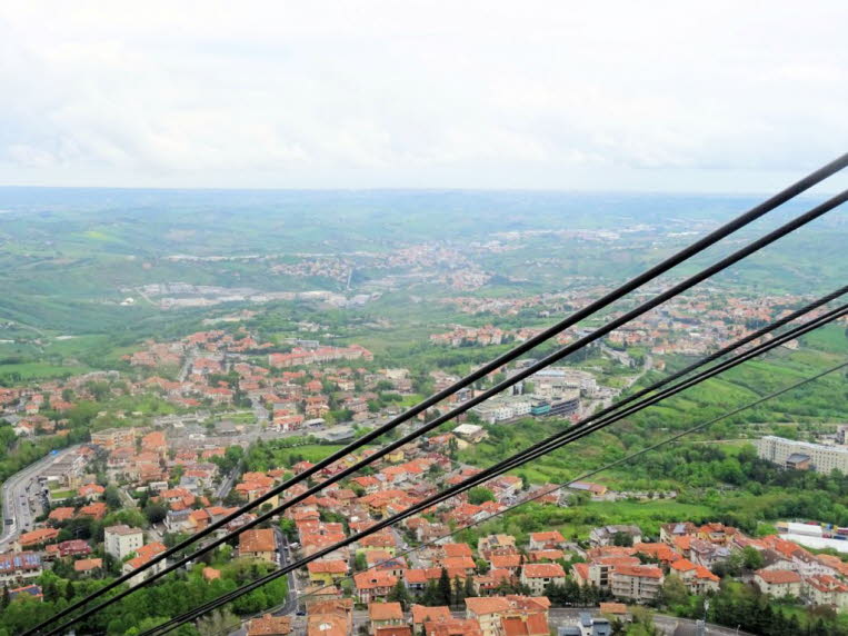 Das Bild zeigt den Blick aus der Funivia di San Marino, einer Kabinenseilbahn, die die Stadt San Marino mit Borgo Maggiore verbindet.Die Seilbahn �berwindet auf einer L�nge von 338 Metern einen H�henunterschied von 166 Metern. Die Fahrt bietet einen Panor