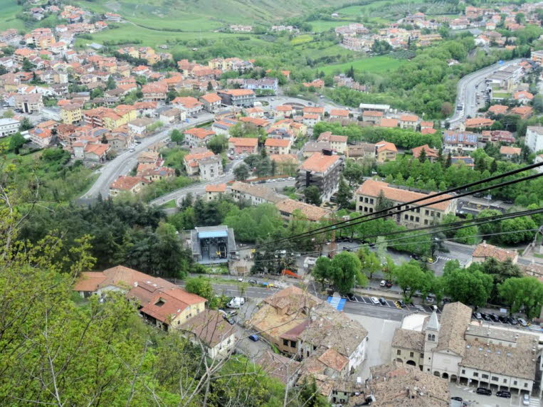 Diese Ansicht zeigt den Blick von der Festung auf dem Monte Titano hinab auf die Gemeinde Borgo Maggiore in San Marino. Verkehrsverbindung: Die im Bild sichtbaren Kabel geh�ren zur Funivia di San Marino, einer Seilbahn, die das historische Zentrum auf dem