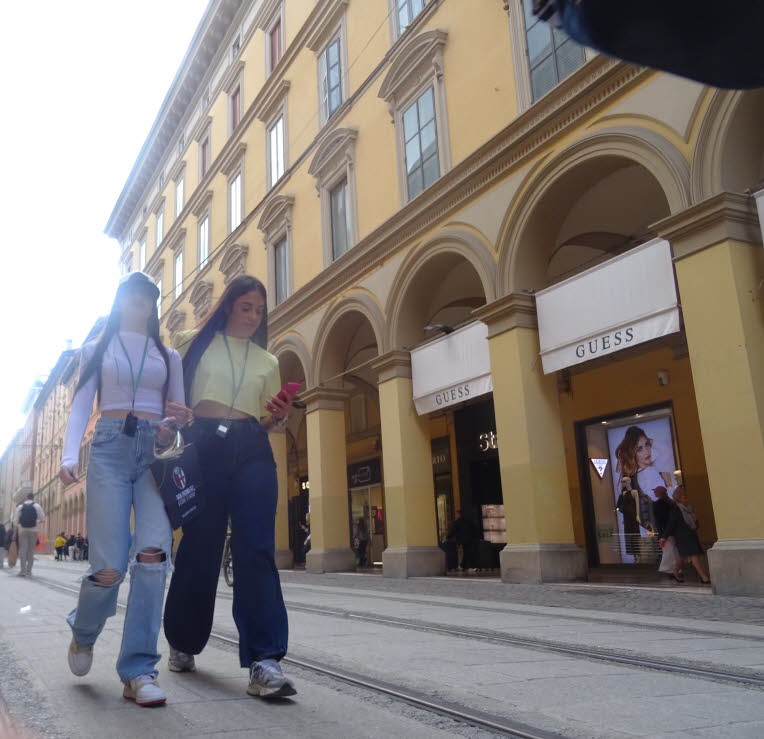 Das ist eine typische Szene aus Bologna: Arkaden, gelber Putz, elegante Schaufenster, Stra�enbahntrasse � und zwei Menschen, die ganz im Alltag versunken sind. Genau diese Mischung aus Architekturgeschichte und beil�ufigem Stadtleben macht solche Fotos sp
