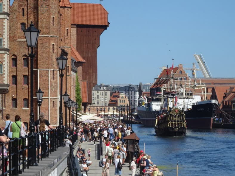 Dieses Bild zeigt die Uferpromenade Dlugie Pobrzeze (Lange Br�cke) an der Mottlau in der historischen Altstadt von Danzig (Gdansk). Das markante Geb�ude im Hintergrund ist das ber�hmte Danziger Krantor. Hier sind einige interessante Details zu diesem Ort: