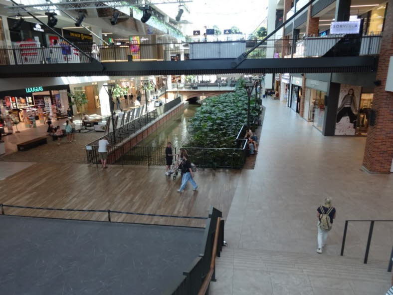 Das Bild zeigt das Einkaufszentrum Forum Gdansk in Danzig, Polen. Ein besonderes Merkmal dieses modernen Geb�udes ist der Kanal in der Mitte, der von Gr�nanlagen und Gehwegen ges�umt wird. Architektur: Das Design verbindet moderne Elemente mit nat�rlichen