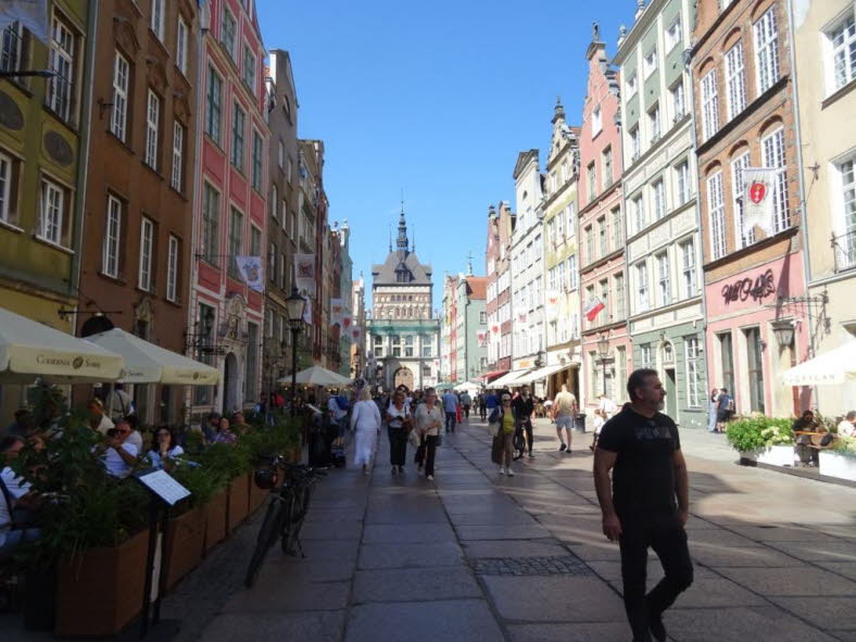 Dieses Bild zeigt den belebten Langen Markt (Dlugi Targ) im Herzen der historischen Rechtstadt von Danzig, Polen. Die Stra�e ist eine beliebte Fu�g�ngerzone, die f�r ihre farbenfrohen, schmalen Giebelh�user im hanseatischen Stil bekannt ist. Hier sind ein