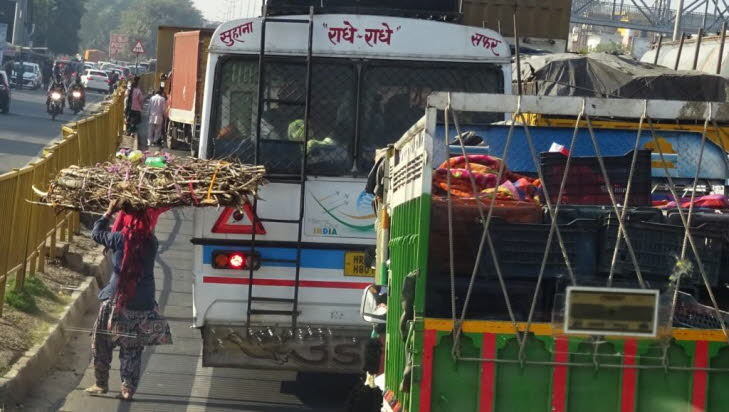 Stra�enszenen in Indien : Auf dem Bild ist eine Stra�enszene aus Indien zu sehen: Am Stra�enrand stehen mehrere Obst- und Gem�sest�nde, mit gut sichtbar aufgeschichteten Fr�chten (z. B. Guaven, Orangen, Zwiebeln). Ein H�ndler mit Preisschildern bietet sei