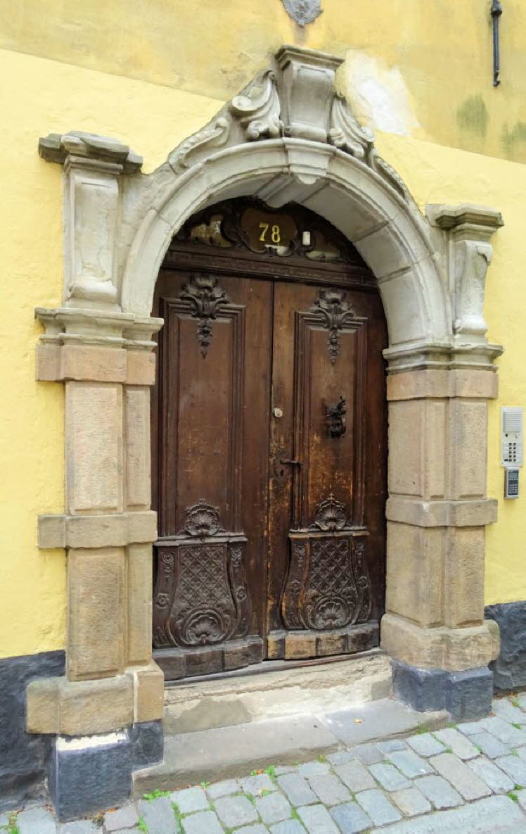 Diese aufwendig geschnitzte alte Holzt�r mit ihrem kunstvollen Steinbogen befindet sich in Gamla Stan, der historischen Altstadt von Stockholm, Schweden.  Das tiefe Holz und das Portal haben charakteristische Schnitzereien und Reliefs, die an Geb�uden aus