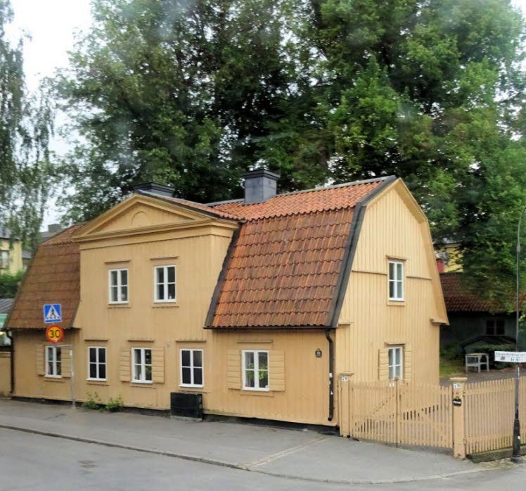 Dieses klassische schwedische Holzhaus in Gelbton besitzt ein typisches Mansarddach mit roten Dachziegeln. Die Holzkassettengliederung der Fassade und die verzierten Fensterl�den verleihen dem historischen Geb�ude seinen traditionellen nordischen Charme.