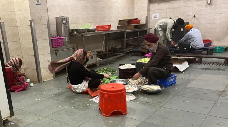 Die Szene zeigt Menschen, die in einer Gemeinschaftsk�che, wahrscheinlich in einem Gurdwara (einem Sikh-Gotteshaus), Gem�se f�r eine Mahlzeit, bekannt als Langar, zubereiten. Langar-Tradition: Die Sikh-Religion praktiziert Langar (eine kostenlose Gemeinsc