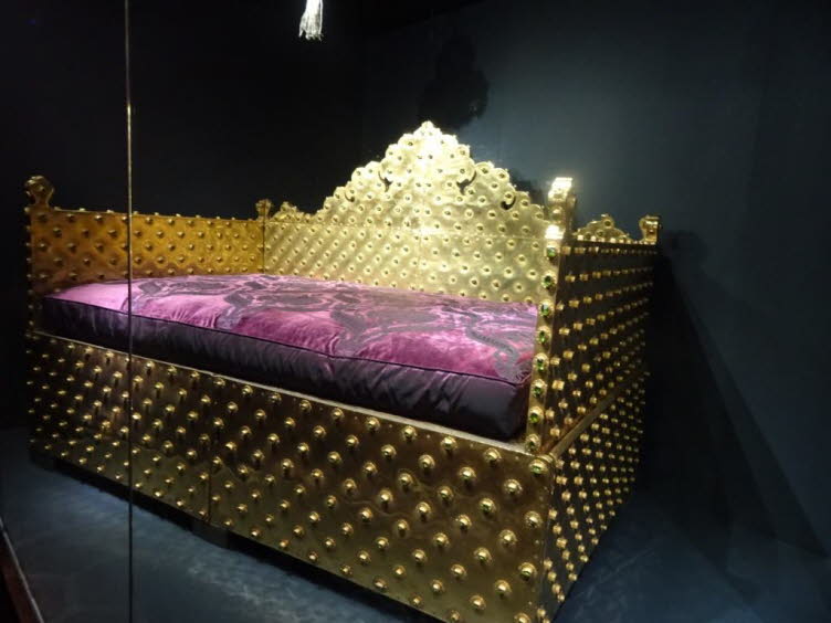 Das Bild zeigt ein historisches Artefakt aus dem Topkapi-Palast in Istanbul, der ehemaligen Residenz der osmanischen Sultane. Es handelt sich um ein pomp�ses Bett oder eine Liege, das wahrscheinlich Teil der Schatzkammer oder des Harems ist. Das M�belst�c