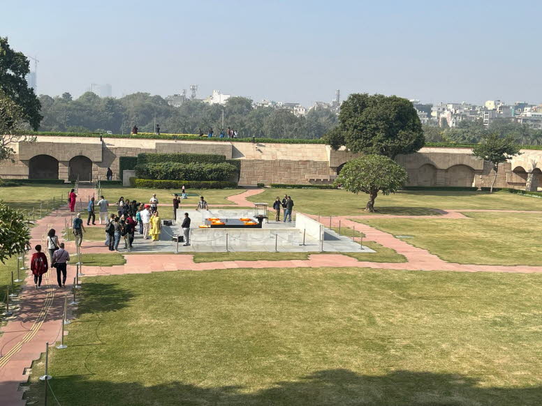Das Bild zeigt das Raj Ghat, eine bedeutende Gedenkst�tte in Delhi, Indien. Es markiert die Stelle, an der Mahatma Gandhi am 31. Januar 1948 einge�schert wurde, einen Tag nach seiner Ermordung. Die Gedenkst�tte besteht aus einer einfachen, quadratischen P