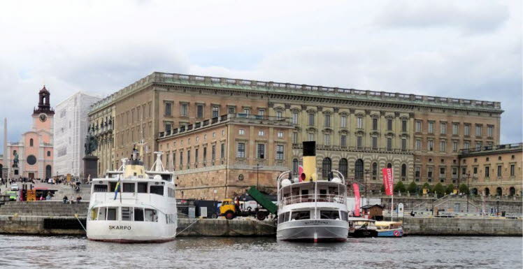 Das Bild zeigt das K�nigliche Schloss in der schwedischen Hauptstadt Stockholm. Im Vordergrund liegen typische Ausflugs- und Passagierschiffe im Hafenbecken.
