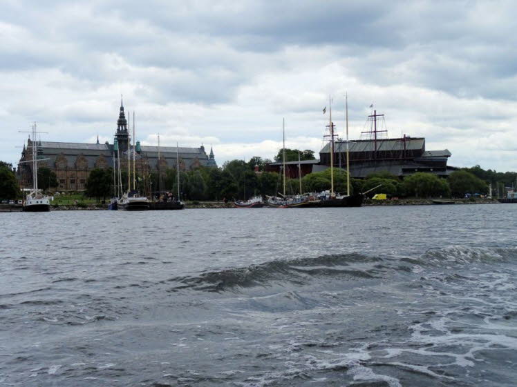 Das Bild zeigt zwei der bekanntesten Museen Stockholms vom Wasser aus: das imposante Nordische Museum (Nordiska museet, links mit dem Turm) und das markante Vasa-Museum (Vasamuseet, rechts mit den Masten) auf der Museumsinsel Djurg�rden.Nordiska museet: S