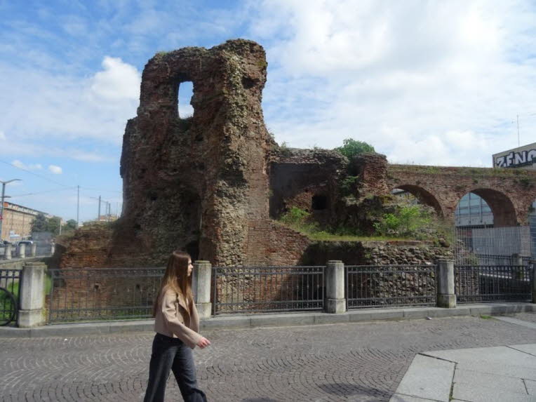 Warum diese Szene kultursoziologisch so stark ist: Weil sie zeigt, wie St�dte Zeit speichern. Die Ruine erz�hlt von Vergangenheit. Die Person erz�hlt von Gegenwart. Die modernen Geb�ude erz�hlen von Zukunft.Alles in einem einzigen Bild. Es ist ein dreidim