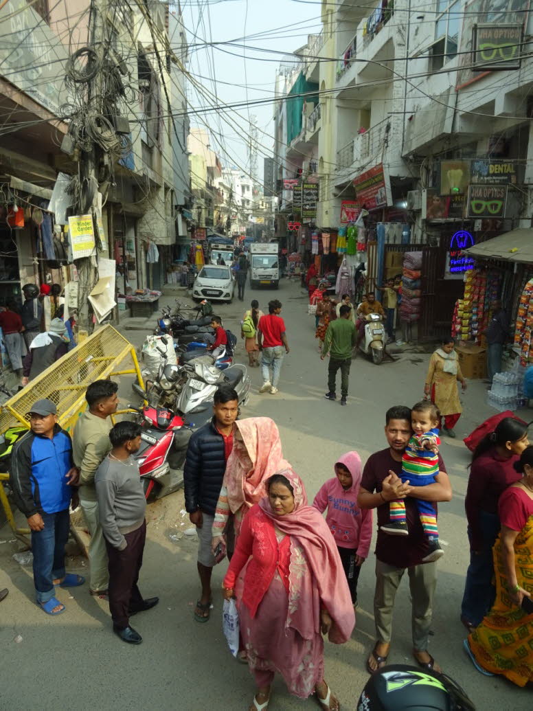 Die Szene im Bild zeigt eine belebte Stra�e, die typisch f�r einen der M�rkte oder Basare in Delhi, Indien, ist. Standort: Die Aufnahme f�ngt das gesch�ftige Treiben und die dichten Geb�ude ein, die f�r die Hauptstadt Indiens charakteristisch sind. Atmosp