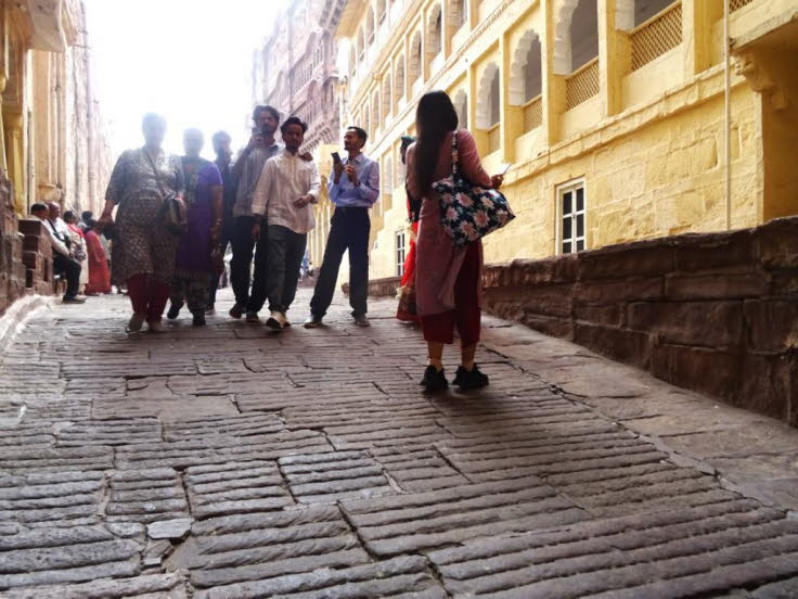 Auf dem Bild ist eine gepflasterte Gasse oder ein Weg innerhalb der Mauern des Mehrangarh Forts Indien, zu sehen. Die Geb�ude bestehen aus charakteristischem gelbem Sandstein und weisen traditionelle indische Architekturelemente wie B�gen und kunstvoll ge