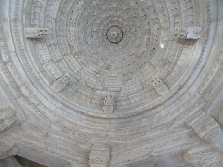 Abgebildet ist die kunstvoll verzierte Decke eines Jain-Tempels in Ranakpur, Rajasthan, Indien. Es geht speziell um die Kuppeldecke des Haupttempels, des Chaumukha Mandir (Viergesichtiger Tempel), der Adinath, dem ersten Tirthankara, gewidmet ist. Wesentl