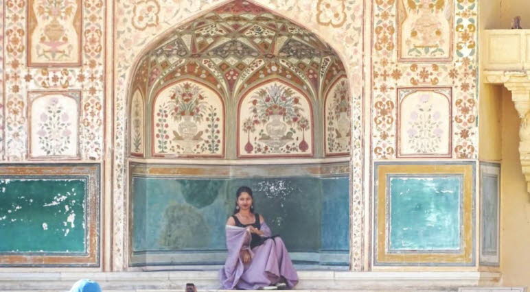 Dies ist ein Schnappschuss, der eine Inderin vor einer kunstvoll gestalteten Nische im Amber Fort in Jaipur, Indien, zeigt. 