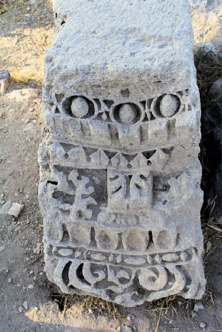 Altes, steinernes Architekturfragment, m�glicherweise eine S�ule oder einen T�rsturz, verziert mit geschnitzten Mustern. Das Fragment weist aufwendige Reliefschnitzereien auf, die geometrische und florale Motive zeigen. Im oberen Bereich sind kreisf�rmige