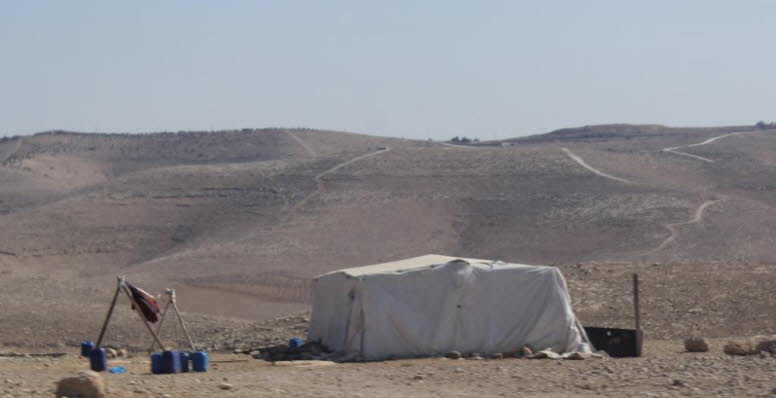 Das Bild zeigt ein Zelt in einer trockenen, h�geligen W�stenlandschaft, das typischerweise als Unterkunft f�r Beduinen dient. Diese Art von Zelt ist eine tempor�re Struktur, die an die extremen Witterungsbedingungen der W�ste angepasst ist. Die Materialie