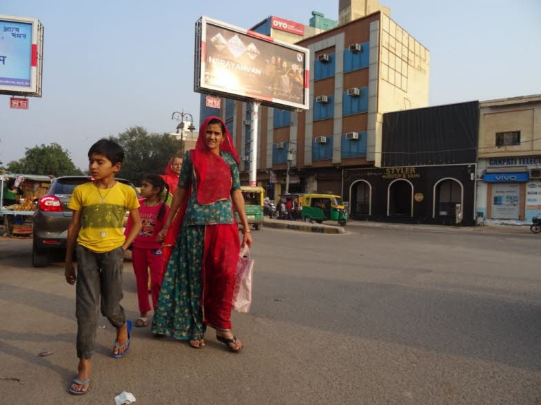 Die Frau auf dem Bild tr�gt traditionelle indische Kleidung, die allgemein als Salwar Kameez oder in dieser spezifischen regionalen Variante als eine Form von Ghagra Choli oder �hnlicher Tracht identifiziert werden kann. Beschreibung: Es handelt sich um e